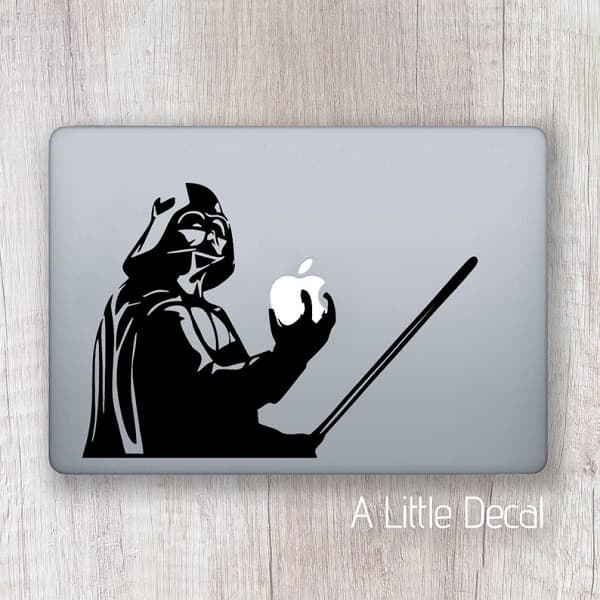 Sticker noir de Dark Vador tenant un sabre laser et le logo Apple du MacBook sur lequel il est collé.