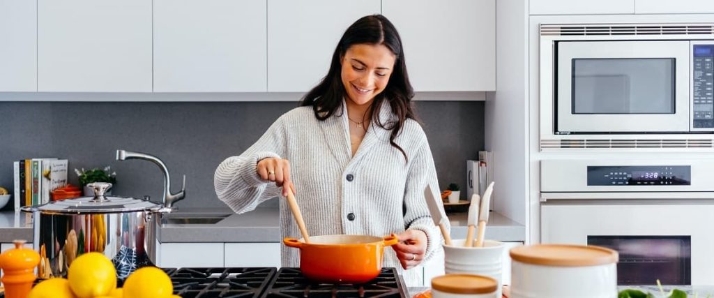 femme cuisinant dans sa cuisine avec une casserole et une louche
