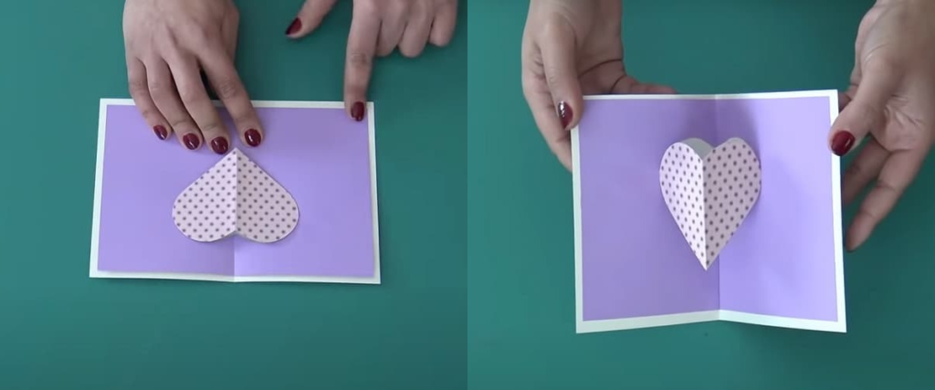 mains collant un carte pop-up cœur avec motifs 
