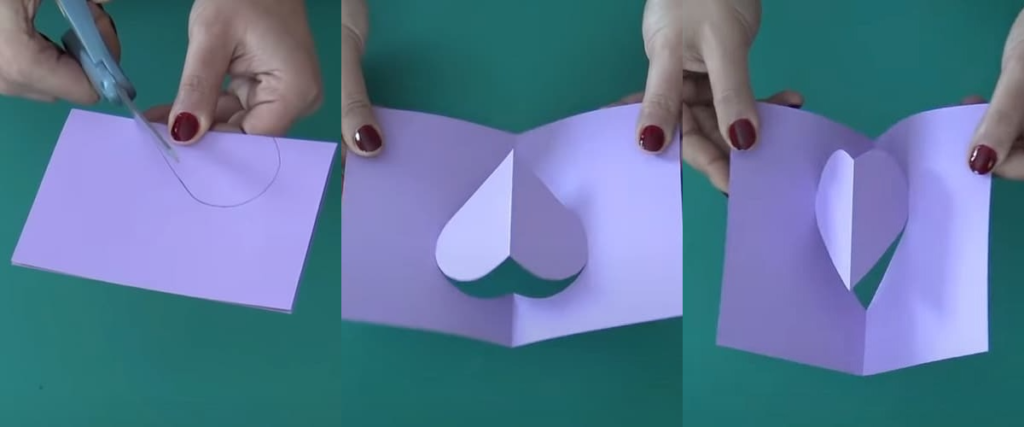 mains découpant un cœur violet dans une carte pop-up violette